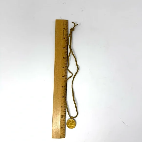 Mayan design gold tone pendant purchased in Costa Rica, on golden suede cord